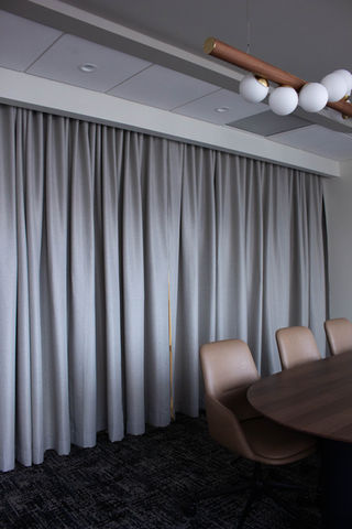 Light grey opaque draperies hung over an interior window in a high-rise office in downtown Denver