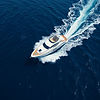 A cinematic shot of a luxury motor yacht sailing through deep blue ocean waters using a dr