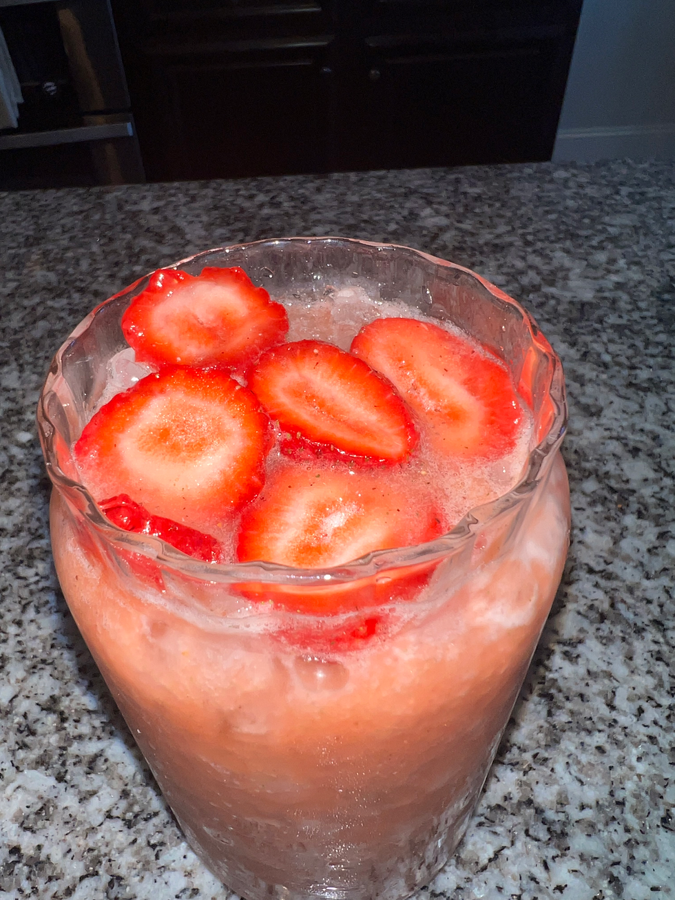 Glass of homemade strawberry kiwi electrolyte drink made with coconut water, honey, lime juice, fresh strawberries, and kiwi over ice.