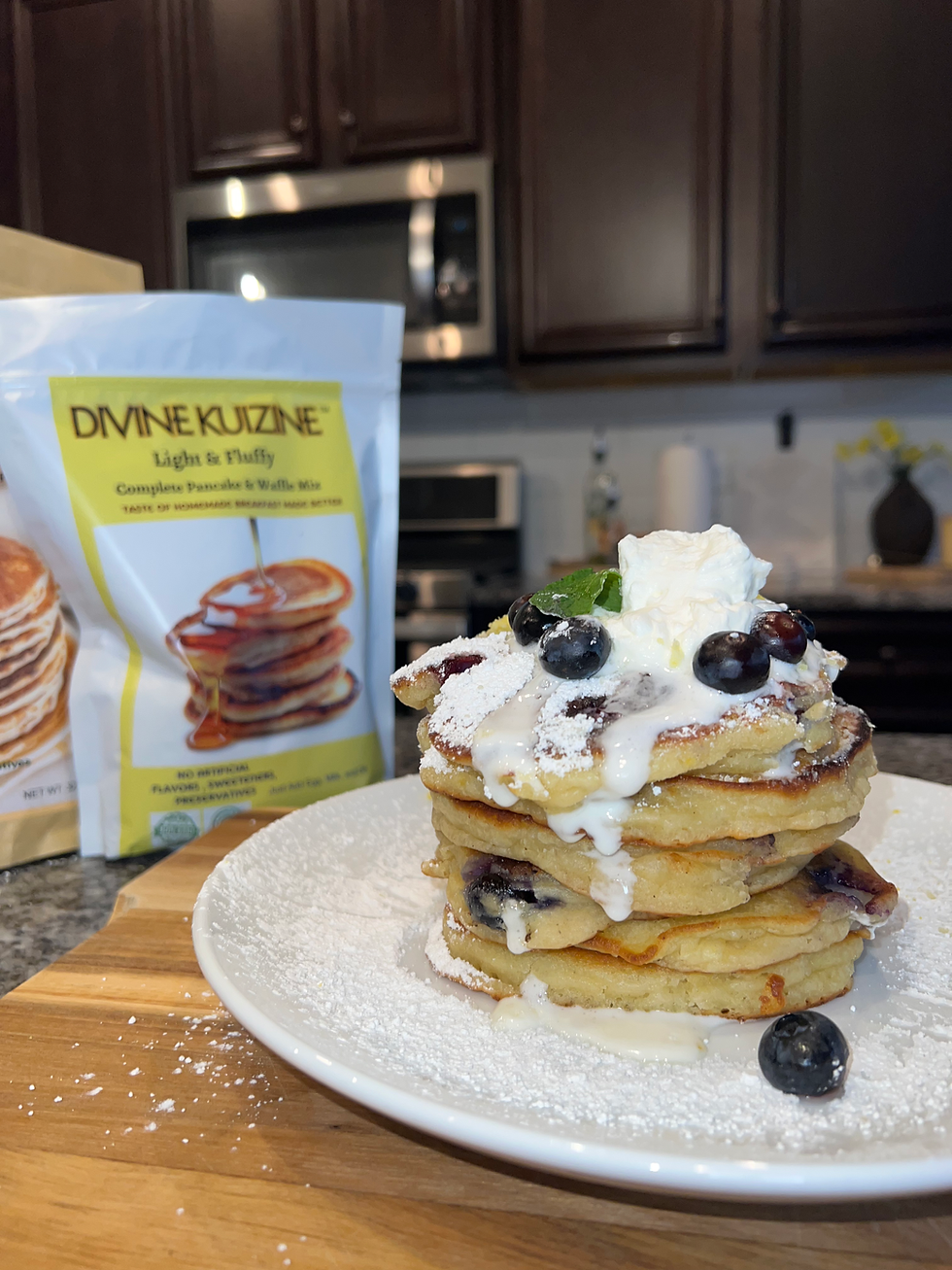 Stack of fluffy lemon blueberry ricotta pancakes topped with homemade vanilla whipped cream, fresh blueberries, powdered sugar, and lemon zest made with DivineKuizine Pancake Mix.