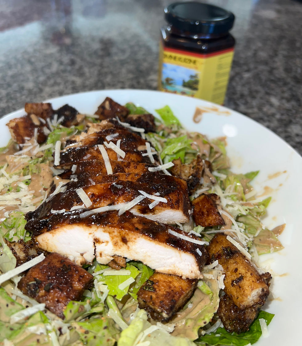 Plated Caesar salad topped with jerk chicken breast, parmesan cheese, and drizzled jerk dressing