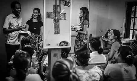 Black and white vignette image of people in a church community room, happily sharing conversation