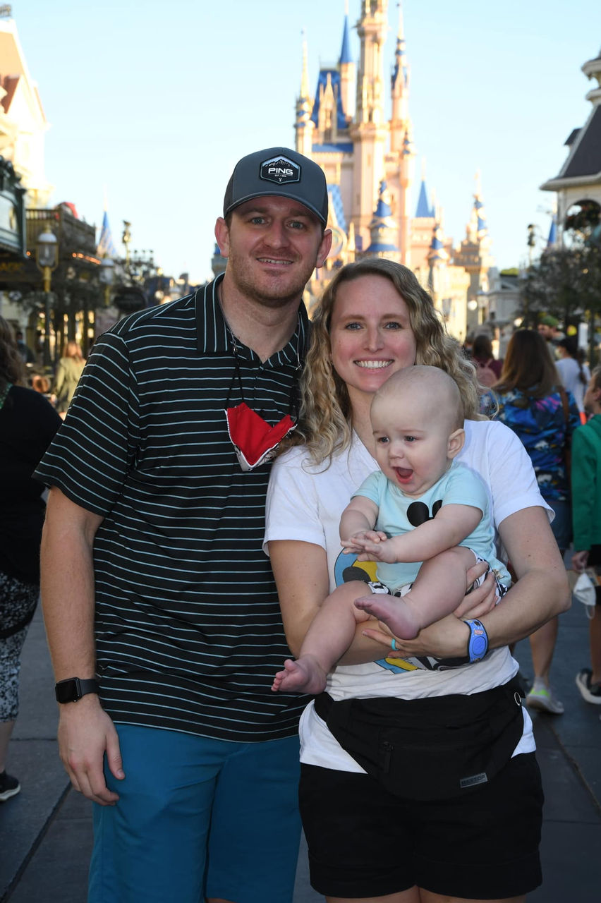 Family smiling with baby at Disney World in front of the castle.