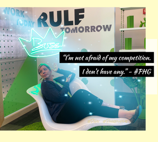 Attractive smiling blonde woman wearing black clothing, lounging playfully on a white chaise, with a glowing neon crown above her head that reads Boss.