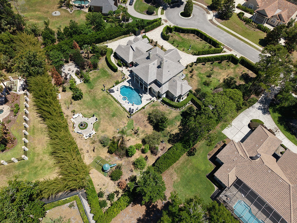 Drone photo of large house with pool and landscaped yard