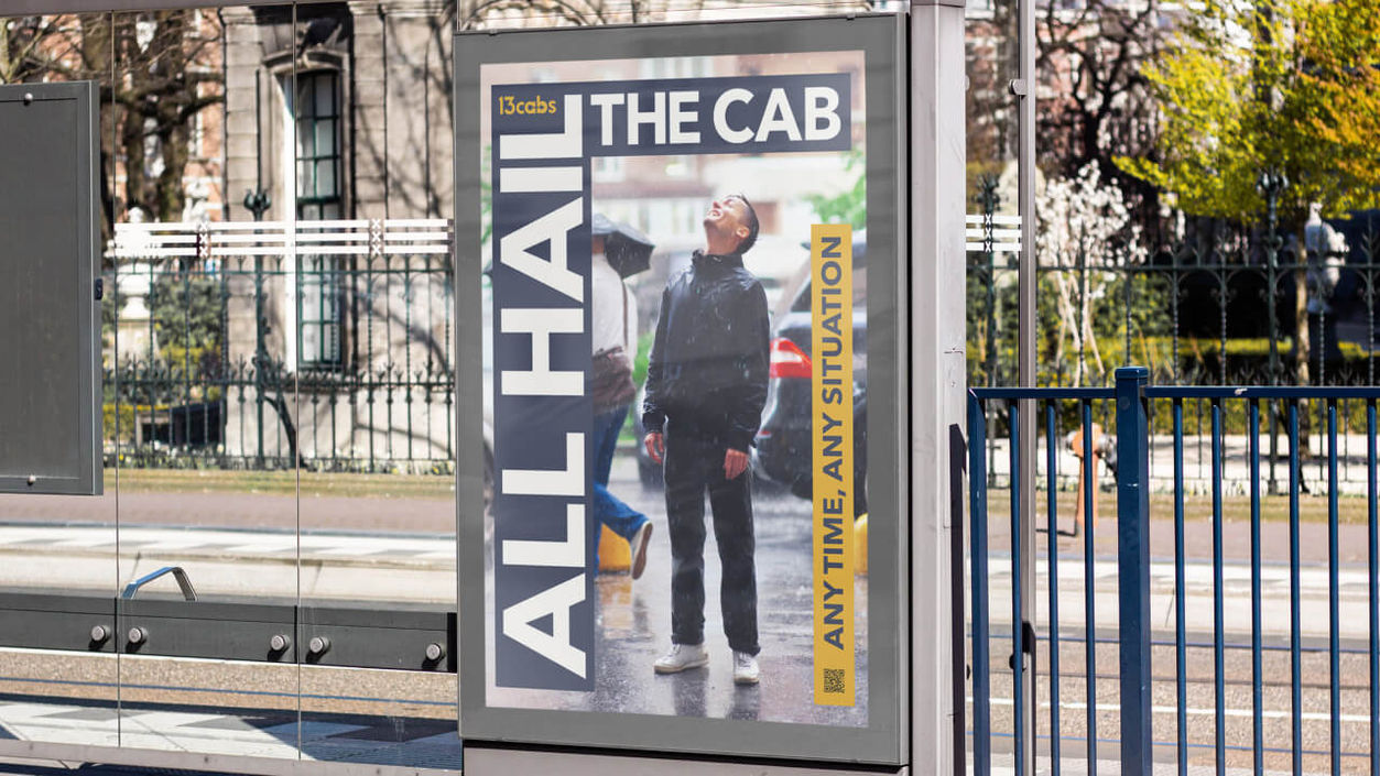 An image of the 'All hail the cab campaign artwork featured on a poster at a bus stop. The poster features an image of a man standing in the rain.
