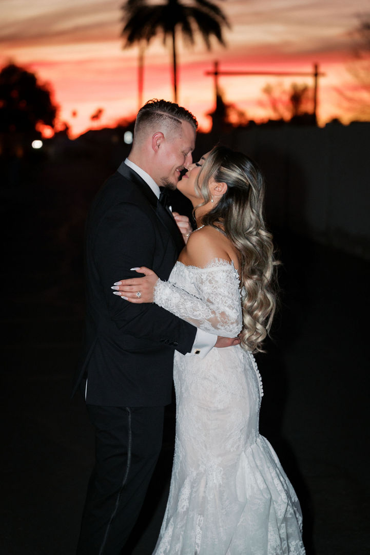 Bride and groom sharing an intimate moment at sunset with palm trees in the background
