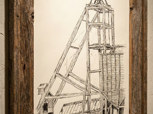 An original graphite pencil drawing by the creator's father, depicting a detailed mining headframe and outbuildings. The sketch is displayed in a rustic, weathered wood frame, serving as the foundational inspiration and namesake for The Graphite Study project.