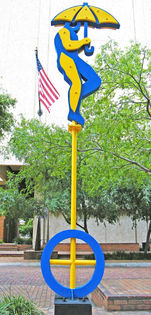 blue and yellow sculpture, a man holding an umbrella on a monocycle. Public Art