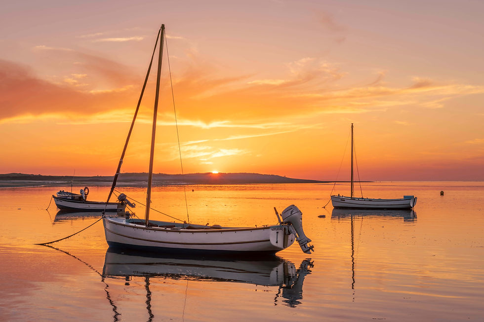 Three boats on tranquil water with a brilliant sunset and orange sky