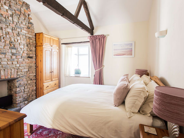 King size bed with cream bedding and feature stone fireplace