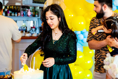 Photographer for birthday party captures mum lighting the birthday cake candles