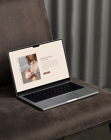 Laptop displaying a website with text; "Inviting you home to yourself", on a chair.