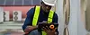 Technician in safety gear inspecting HVAC units on a roof