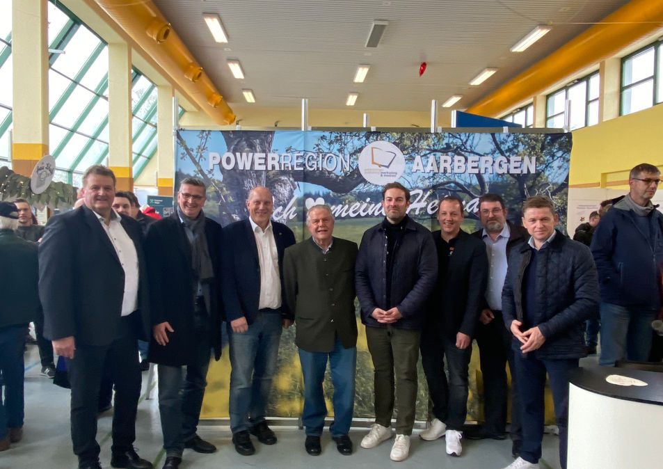 Gruppenfoto aller politischen Vertreter, die lächelnd und gut gelaunt vor der farbenfrohen Heimatwand während der Gewerbeschau stehen. Powerregion Aarbergen - entdecke das Potential deiner Region.