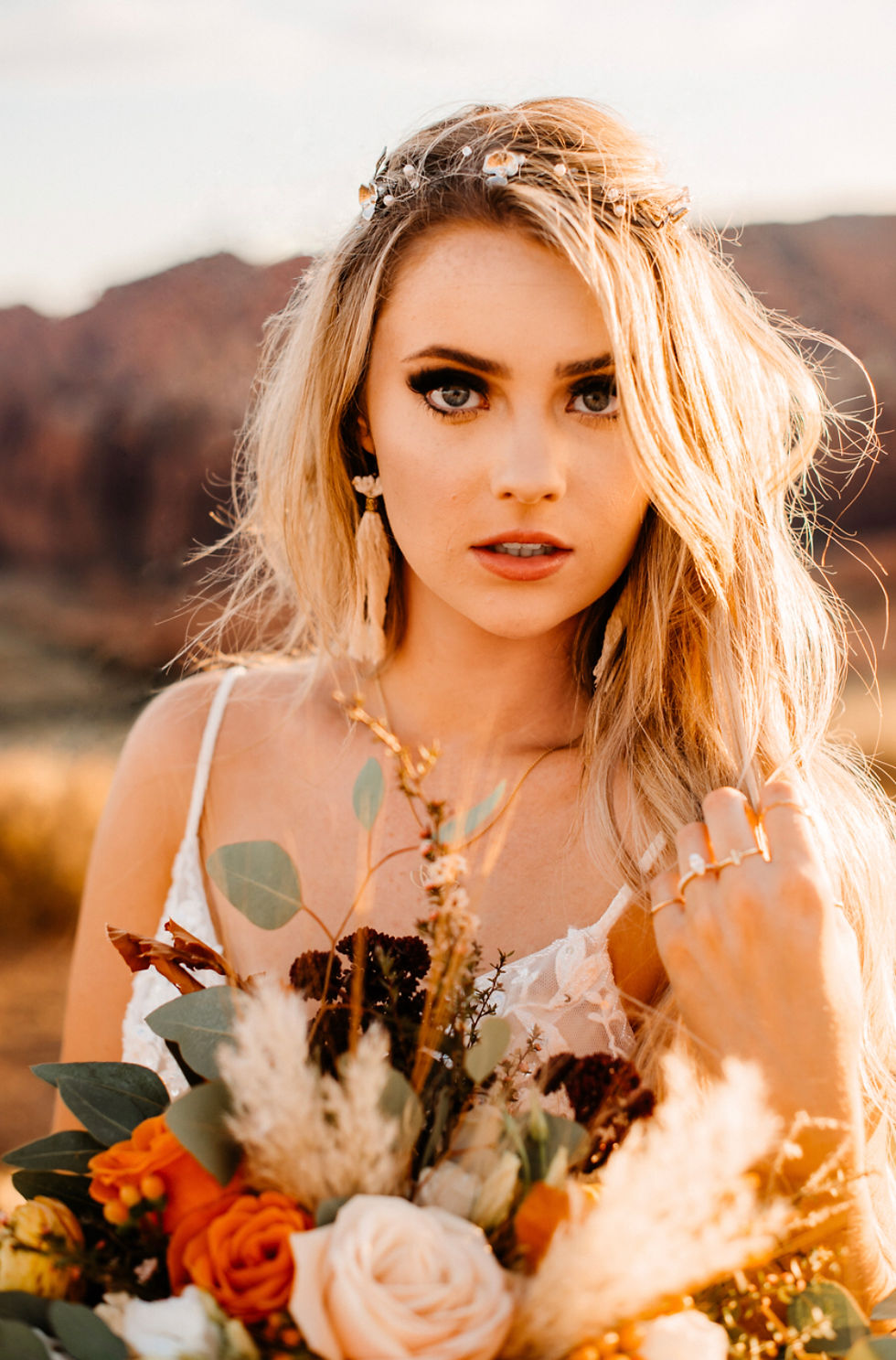 Golden Hour bridal photography in Zion National Park holding her bouquet of flowers and showing her wedding Jewelry. #weddingjewelry #outdoorwedding #utahwedding #weddingflowers #bridalbouquet #snowcanyonstatepark #snowcanyonstateparkwedding #destinationelopement #bridalphotos #weddingphotography #weddingplanner #utahweddingplanner