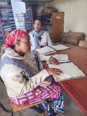 Two women reading Braille books at AHCB