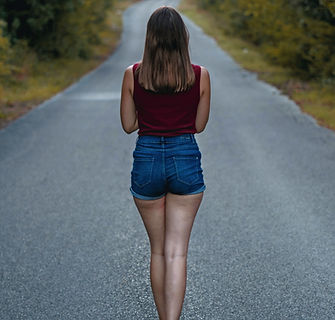 a woman walking down the middle of a roa