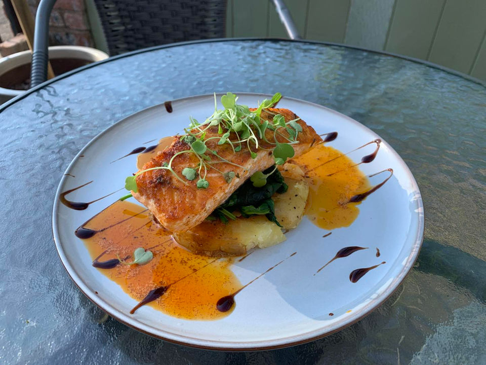 Pan Fried Salmon A La Gallega with garlic, sweet paprika & white wine sauce, sliced potatoes, & wilted spinach.