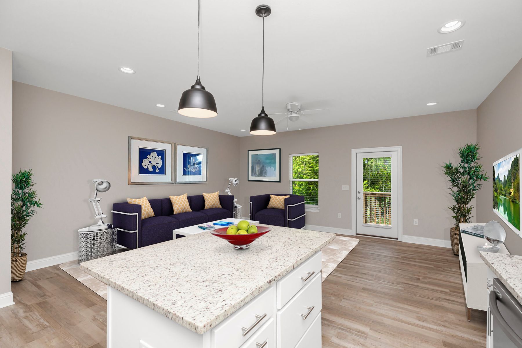 Open living area with a granite kitchen island, wood-look floors and a door to the back patio