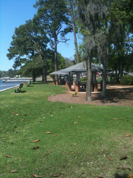Shaded picnic pavilion and benches on a lawn beside the bayou