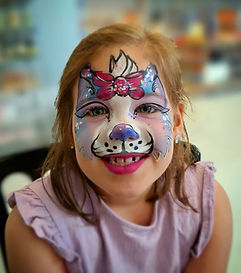 High-end retail event entertainment featuring a smiling kid with a detailed cat face paint character design at a corporate VIP shopper instore promotion