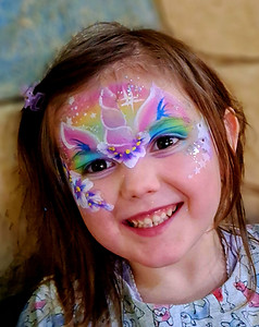 A happy child smiling with a custom unicorn face paint design at a children's birthday party in Edinburgh styled by Event Buddies Scotland
