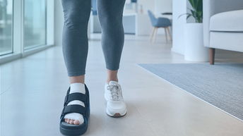 Paciente caminando con zapato postoperatorio durante la recuperación de una operación de juanetes