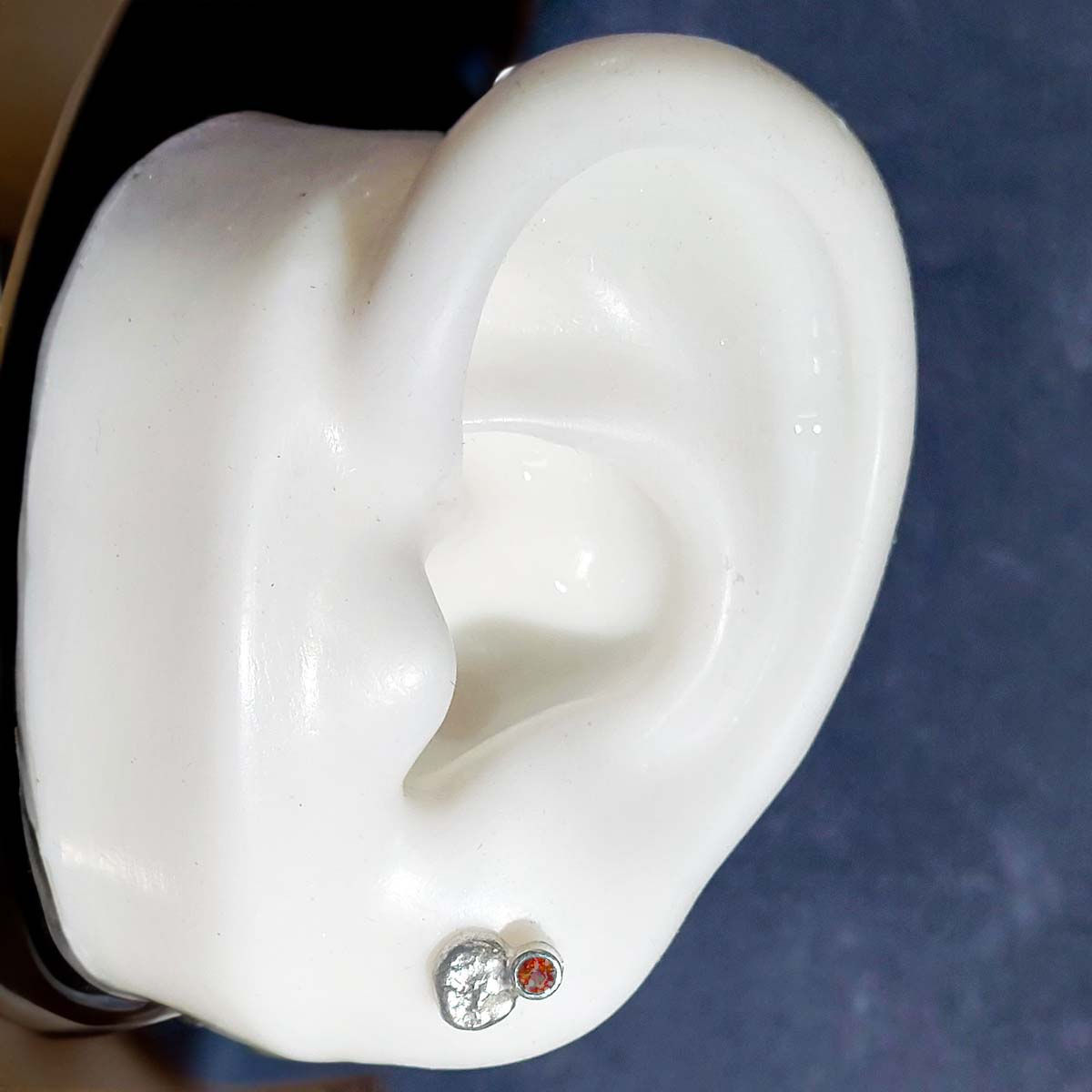 silver textured little stud earrings in figure 8 shape with garnet set in top.