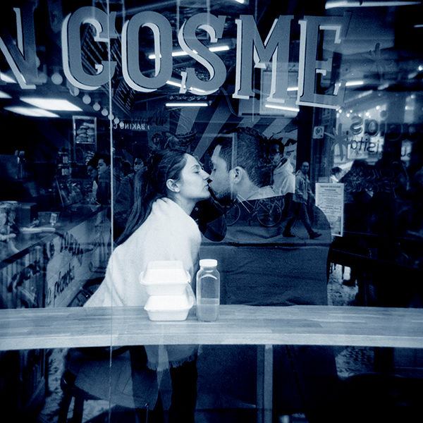 The Kiss—gum-over-cyanotype print of two people kissing inside a cafe, with the words Cosmic on the storefront glass