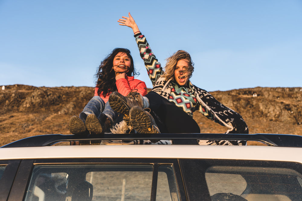 Girls sitting on the roof of a car