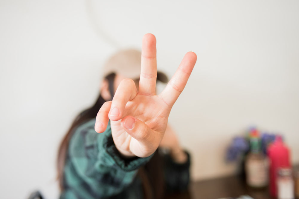Girl pulling peace sign to say hello