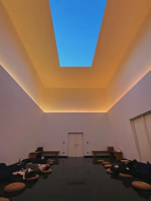 Visitors lying under the soft daylight inside the Gathered Sky light installation