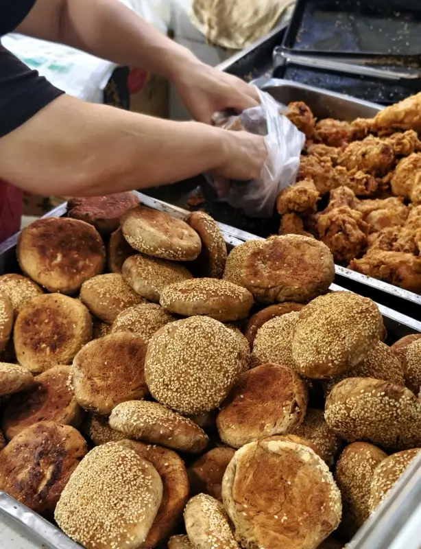 Sesame-coated shaobing and fried snacks being prepared at Manji Shaobing on Niujie Street in Beijing