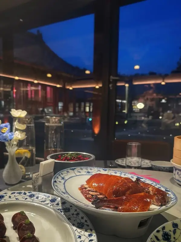 A dining table by the window with evening lights and traditional rooftops in the background.