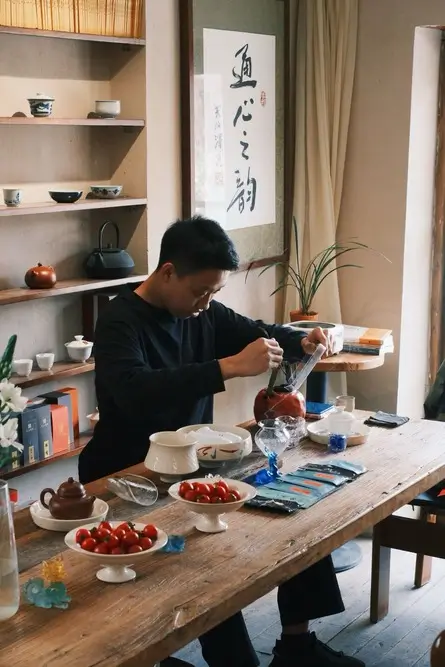 Man performing a traditional Chinese tea ceremony at a wooden table with teaware in a minimalist tea
