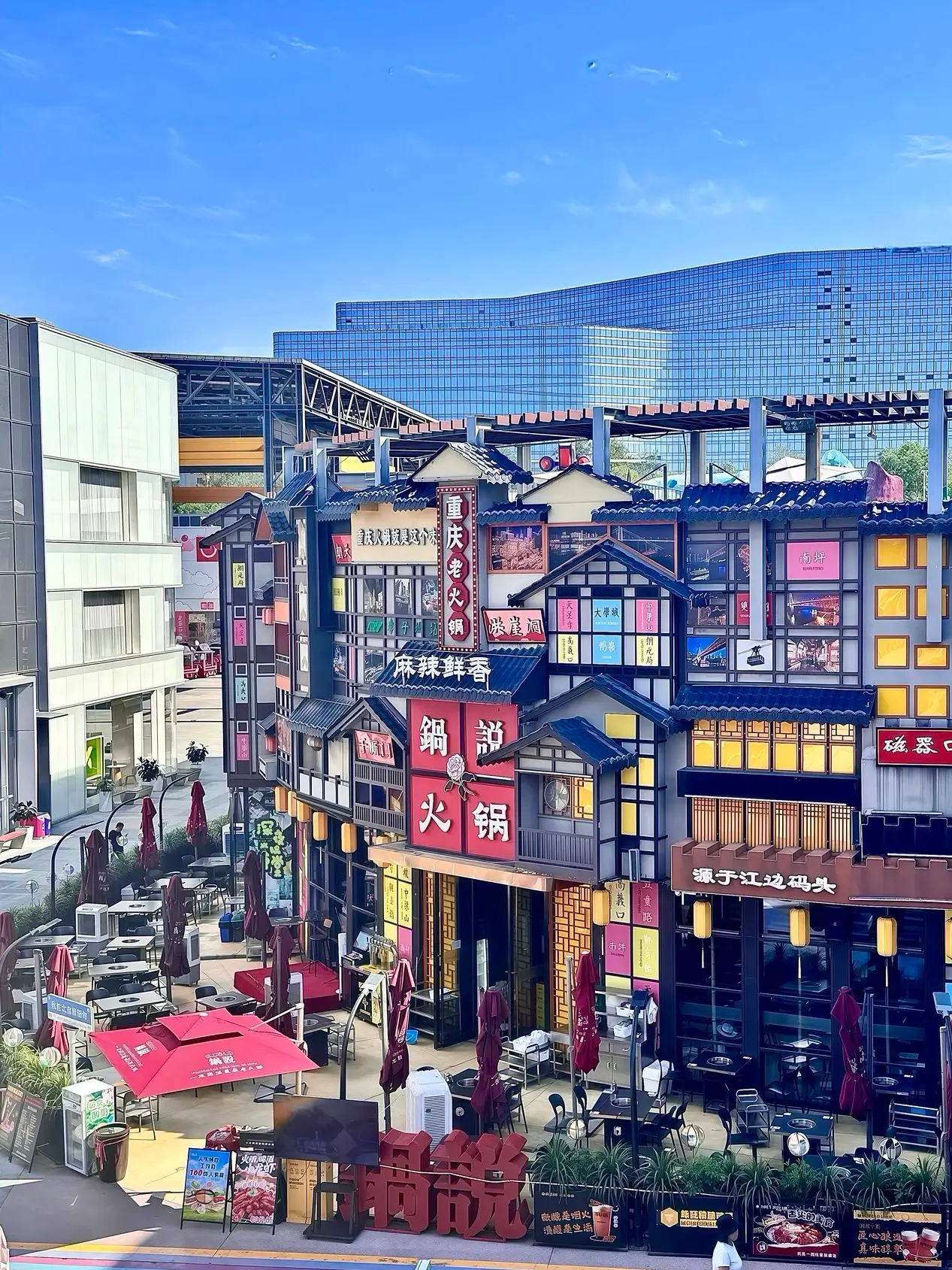 Huaxi LIVE Wukesong food street with traditional-style facades, bright signage, and modern glass buildings in the background in Beijing