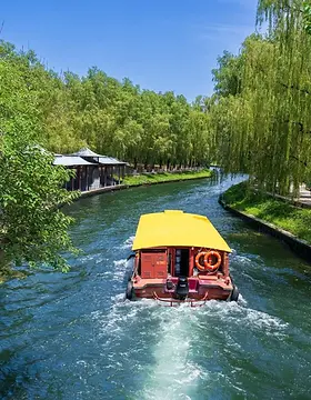 BiteEscape Beijing private tour – boat cruising along a shaded canal from Zizhuyuan Park toward Summer Palace, surrounded by willow trees and peaceful waterway views