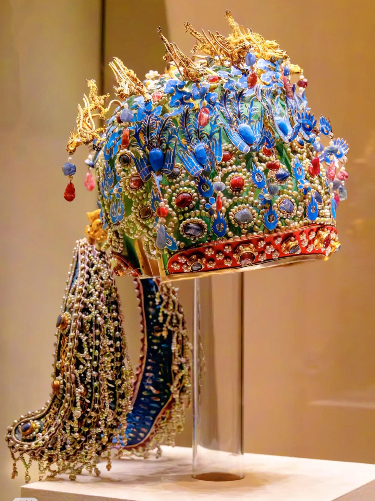 Imperial cloisonné crown with rich blue enamel, intricate floral patterns, gemstones, and cascading pearl tassels, showcasing traditional Beijing craftsmanship.