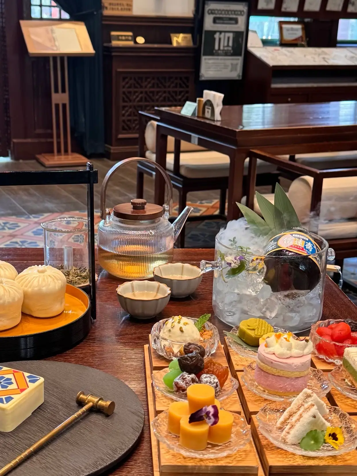 Glass teapot, teacups, and elegant Chinese pastries served on a table in a refined traditional teaho