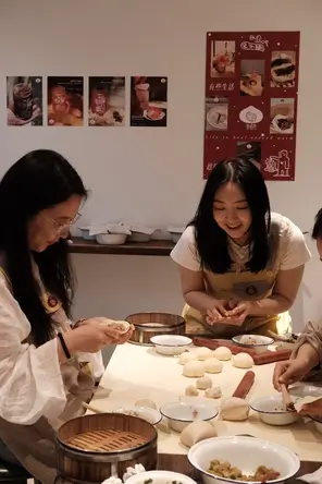 Guests learning how to shape and fold handmade Chinese buns during Bite Escape's interactive Hutong Bun Making Experience, combining local food culture with a fun cooking workshop in Beijing.