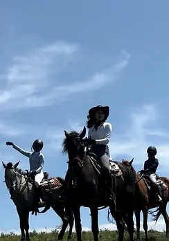 Horseback riders posing with their horses under a blue sky during a two-day riding camp near Beijing.