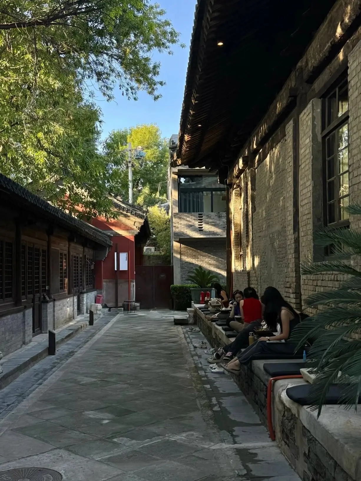 Visitors sitting in a quiet courtyard beside a historic temple building in Beijing