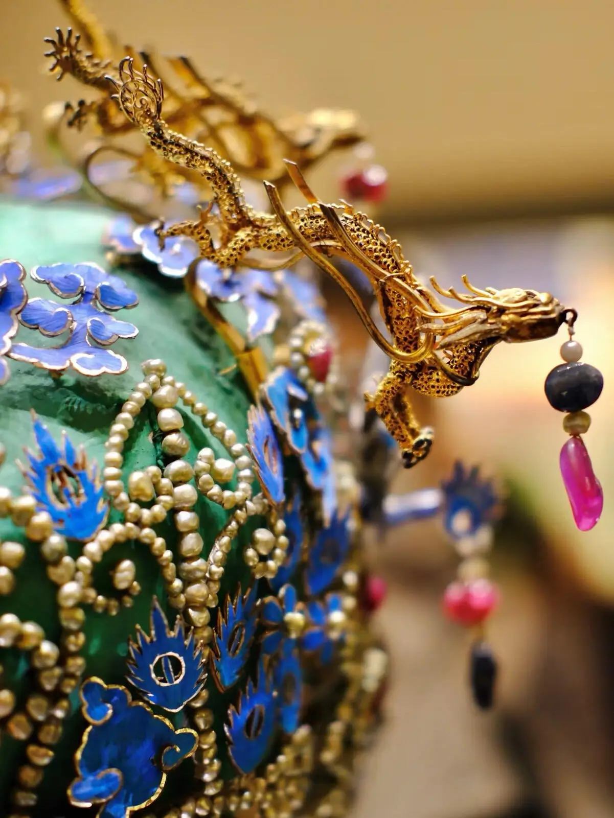 Close-up of a golden dragon ornament on a cloisonné piece, with detailed enamel work and hanging bead decorations, highlighting fine Beijing cloisonné artistry.