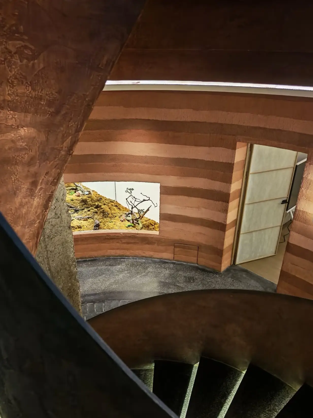 Spiral stairway and curved earthen walls inside a uniquely designed cave-style interior space