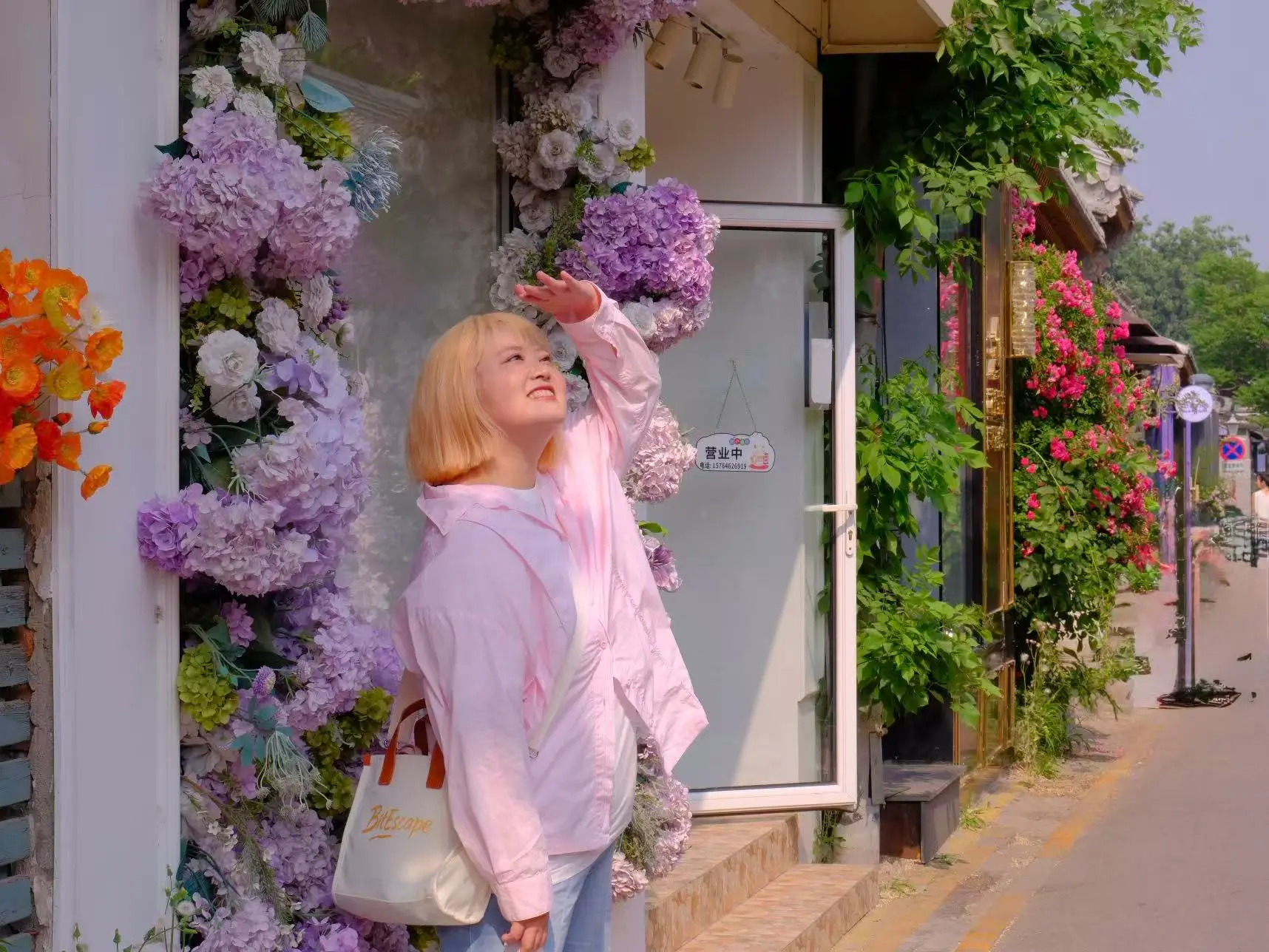 A traveler walking through Wudaoying Hutong in Beijing, surrounded by flowers, small shops, and greenery.