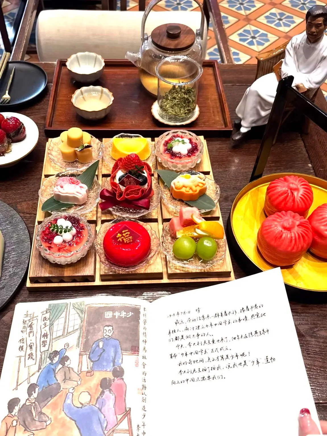 Traditional Chinese tea set with colorful handcrafted desserts, fruit-shaped pastries, and tea leave