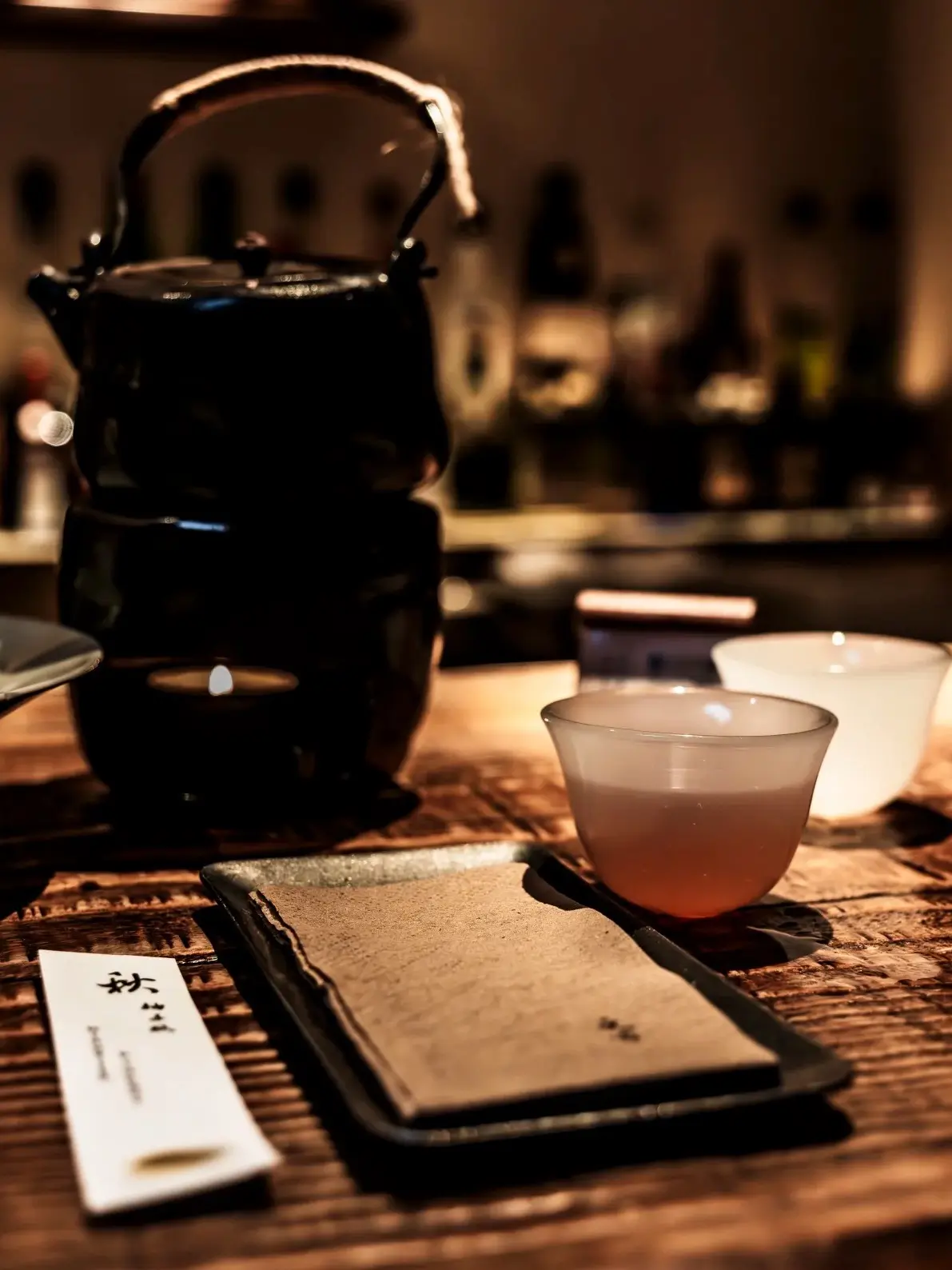 Traditional Chinese teapot and teacup with warm amber tea on a wooden table in a cozy dimly lit teah