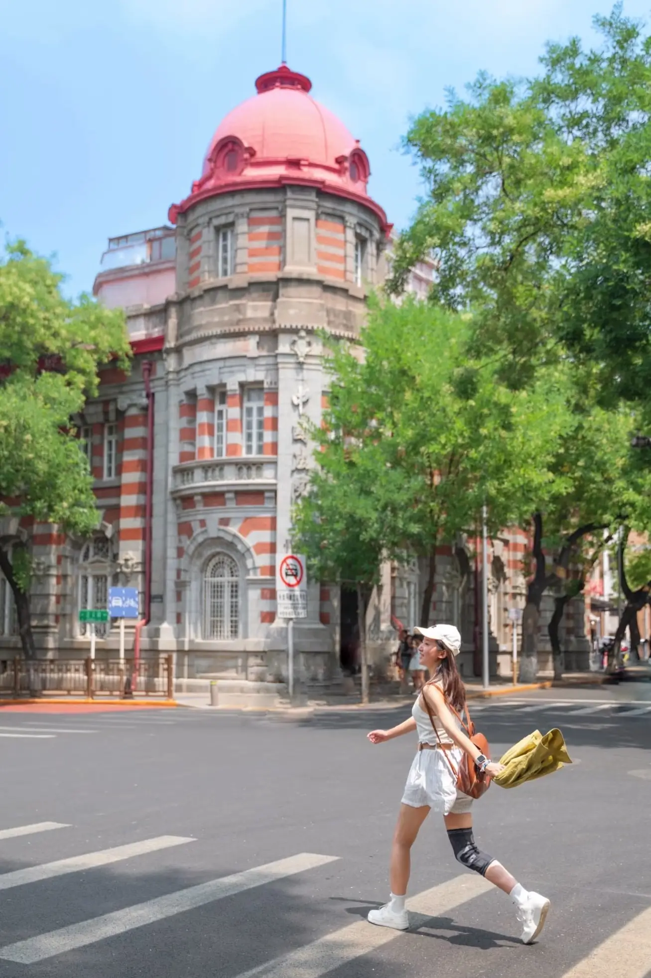 Traveler crossing the street near historic European-style architecture in Xijiao Minxiang, one of Beijing’s oldest hutong areas near Tiananmen
