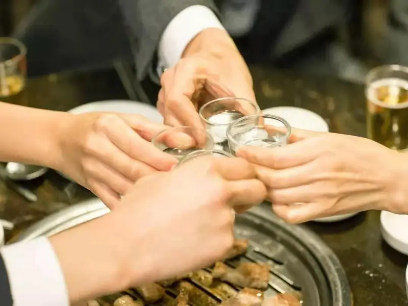 Observing gānbēi toasting etiquette, lowering the glass as a sign of respect.